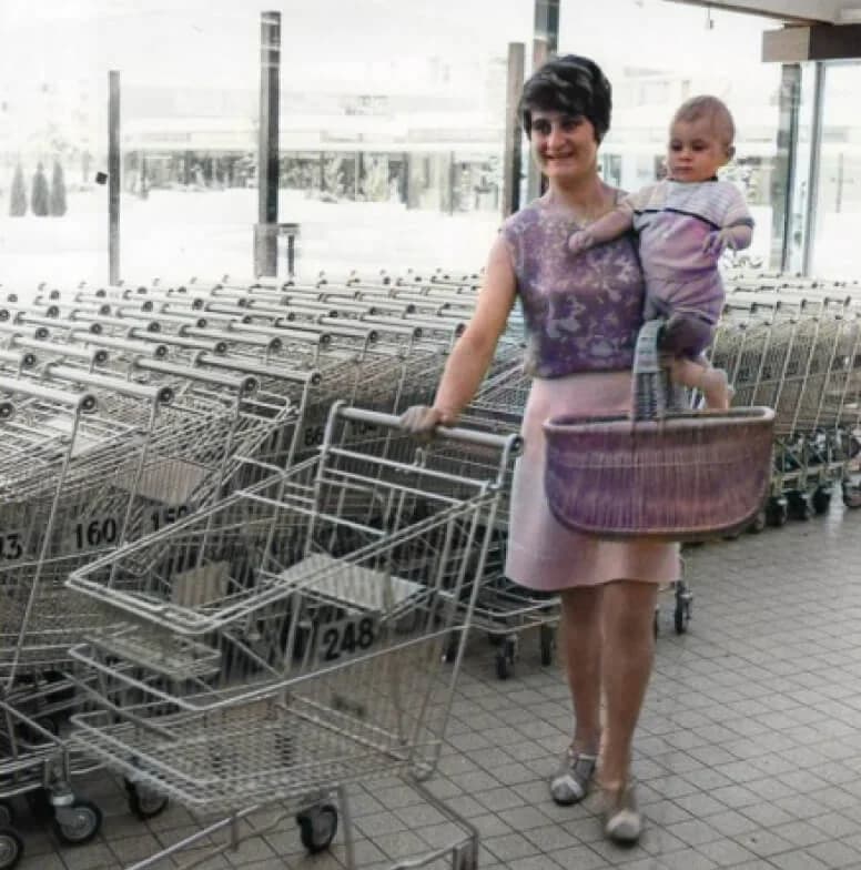 Archival photograph of a shopper and child beside supermarket trolleys